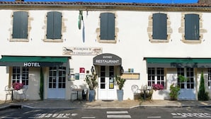 A building with a sign for a hotel and a restaurant. There are outdoor seating areas with tables and chairs. - Auberge La Crémaillère (Villandraut)