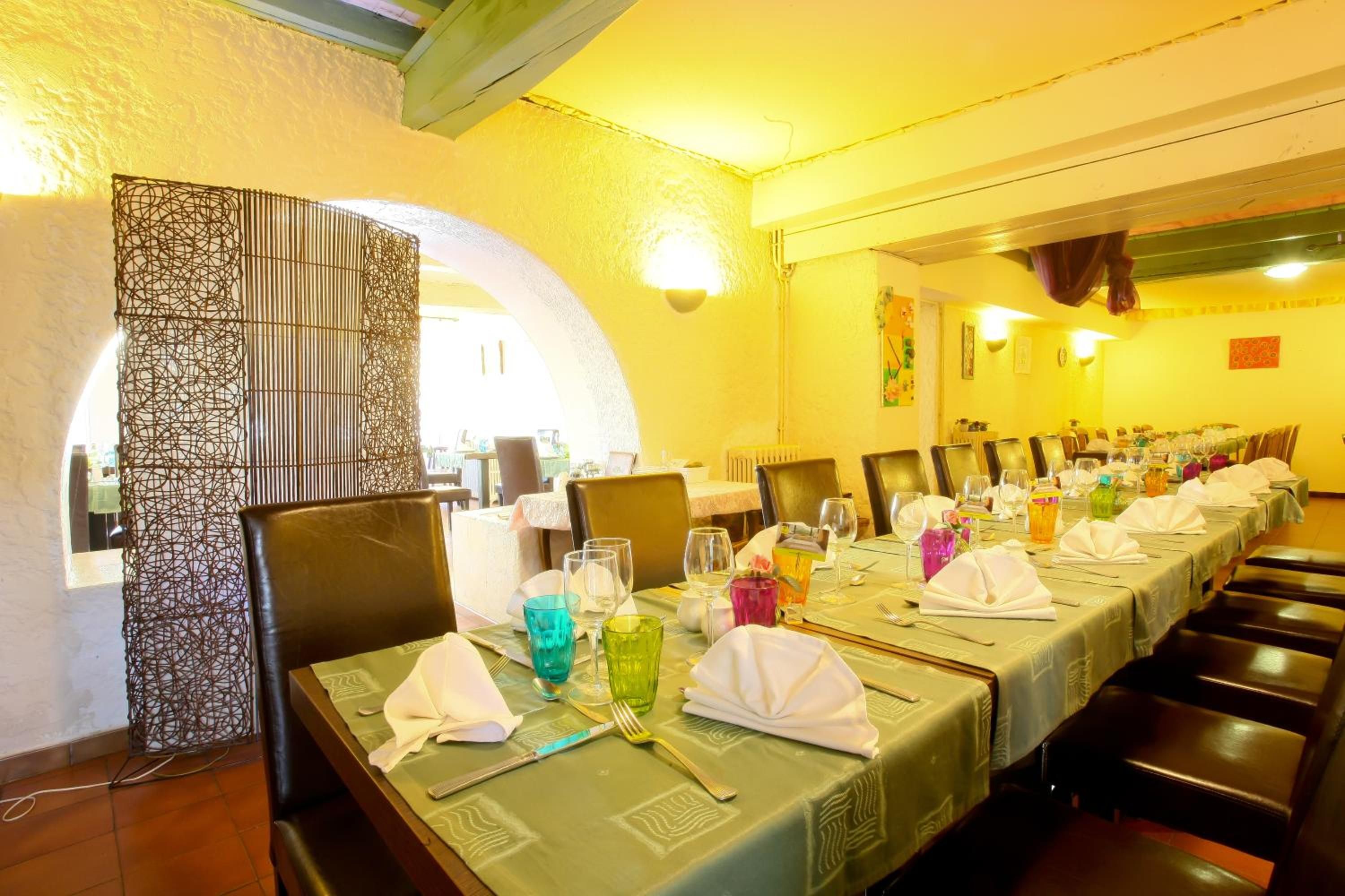 A long dining table set for a meal with chairs, a decorative wall, and a window in the background.