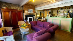 A cozy living room with a fireplace, a bar area with a Buddha statue, and a stone wall. - Auberge La Crémaillère (Villandraut)