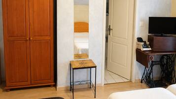 Un dormitorio con un armario, una mesita, un televisor y una máquina de coser.