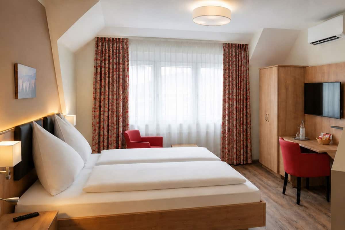 Een hotelkamer met een bed, een bureau, een televisie en een douche.