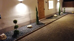A building with a wooden door, a window, and a pathway with small plants and rocks. - Landgasthof Niebler (Adelsdorf)