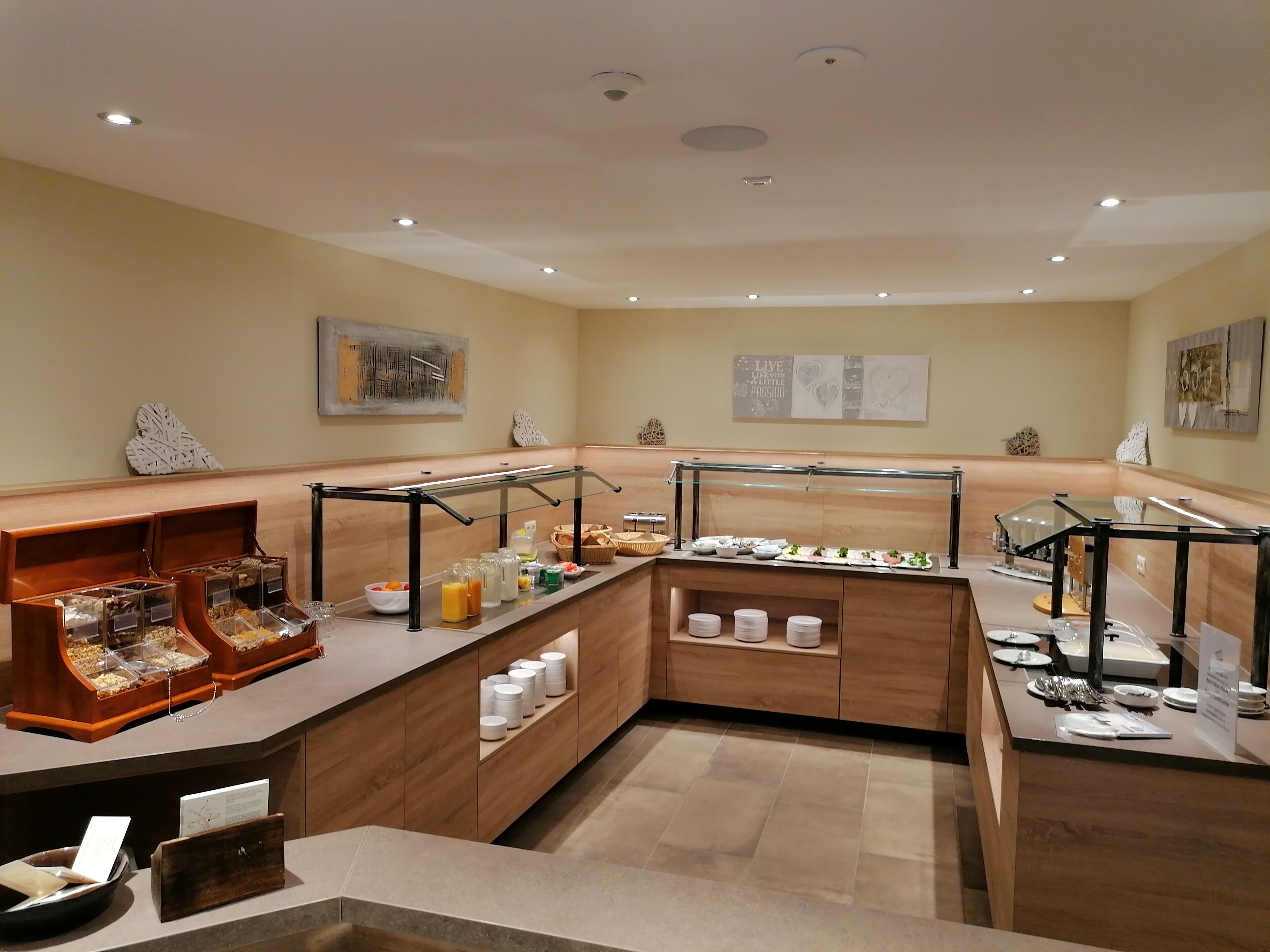 Un área de desayuno de hotel con un buffet variado, que incluye diversos alimentos y bebidas, y un diseño moderno y limpio.