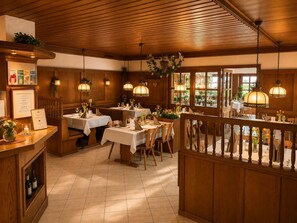 Restaurante com interiores em madeira, mesas com toalhas brancas e luminárias pendentes.