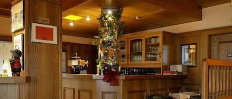 Una zona de bar con armarios de madera, una barra y una decoración navideña.