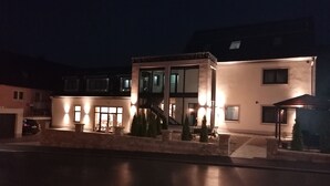 A modern two-story house with a garage, a covered outdoor seating area, and a well-lit entrance. - Landgasthof Niebler (Adelsdorf)