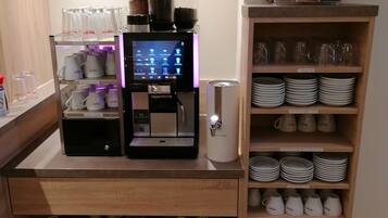 Eine Kaffeestation mit einer Kaffeemaschine, Tassen und verschiedenen Kaffeekapseln.