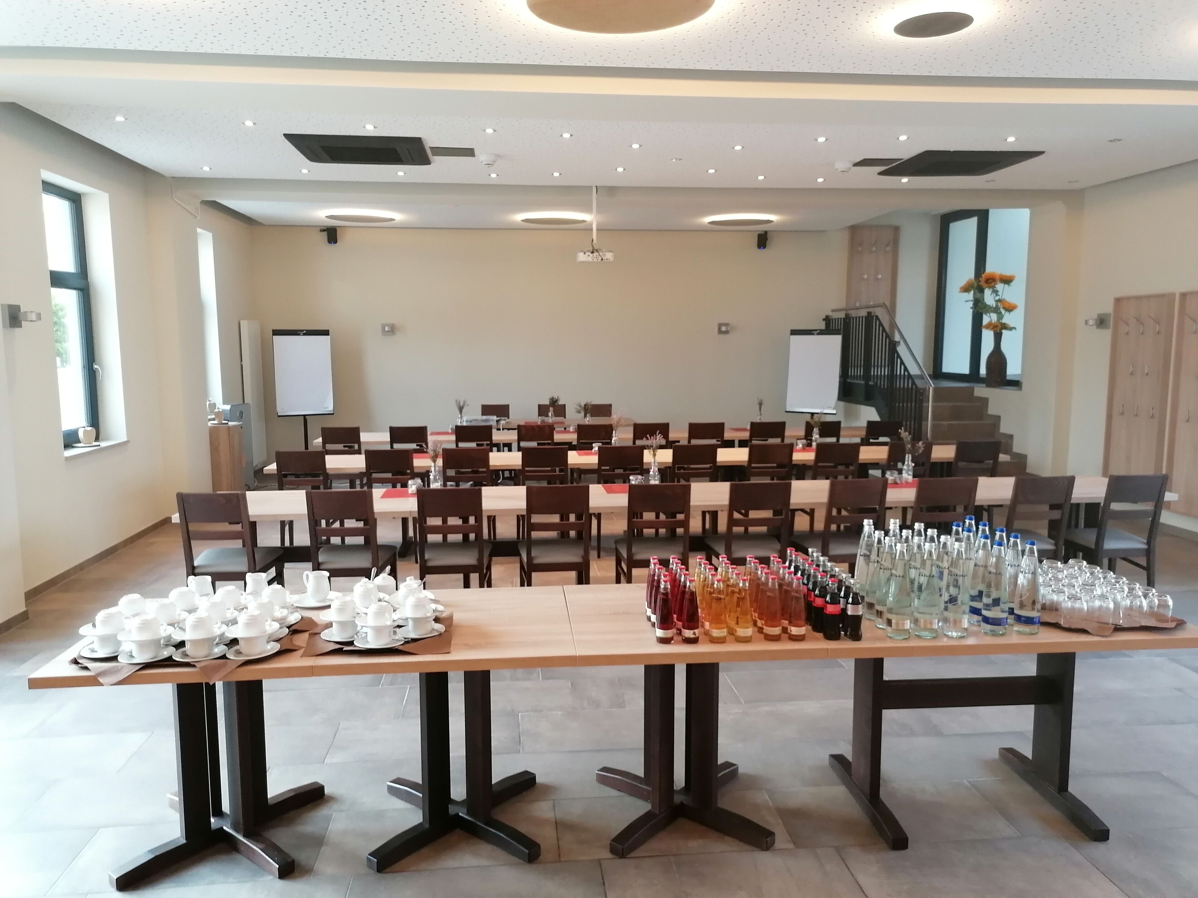 Une salle de conférence équipée de plusieurs tables, de chaises et d’une estrade.