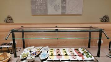 A buffet setup with various food items and a motivational poster on the wall.