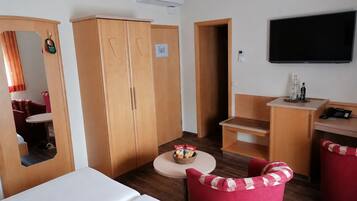 A hotel room with a bed, a desk, a chair, a television, and a wardrobe.