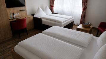 A hotel room with two beds, a desk, a TV, and a window with curtains.