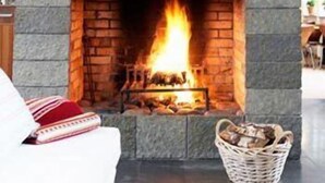 A fireplace with a stone facade, a wooden mantel, and a visible fire.