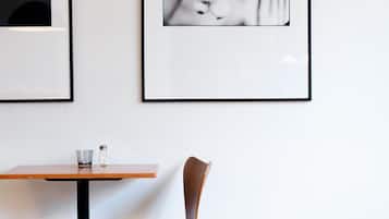 Un coin repas avec une table et deux chaises, des photographies en noir et blanc encadrées au mur et un plancher en bois.
