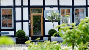A traditional half-timbered building with a tiled roof, a wooden door, and two potted plants.