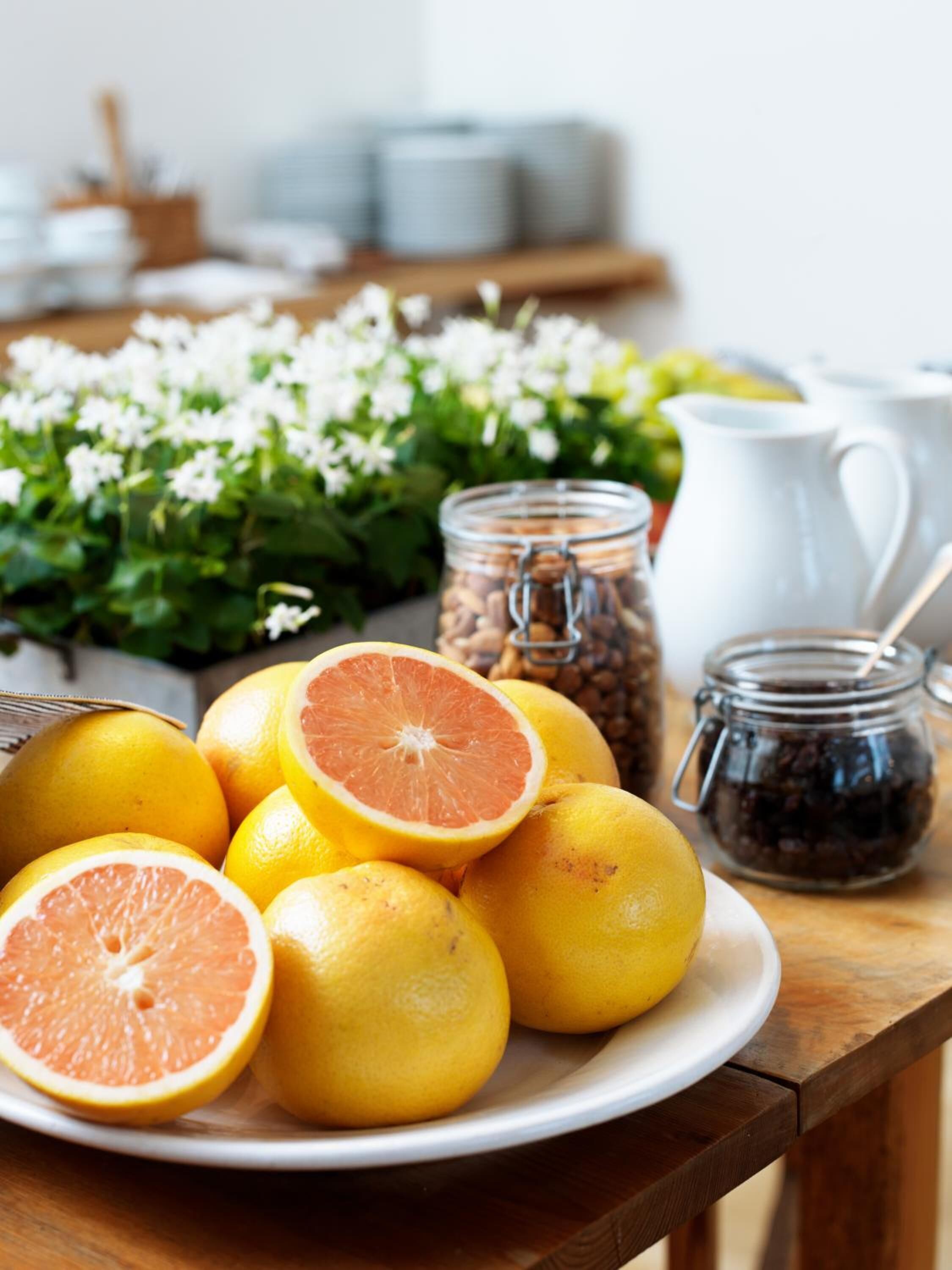 A plate of oranges and a half-cut orange on a wooden table.