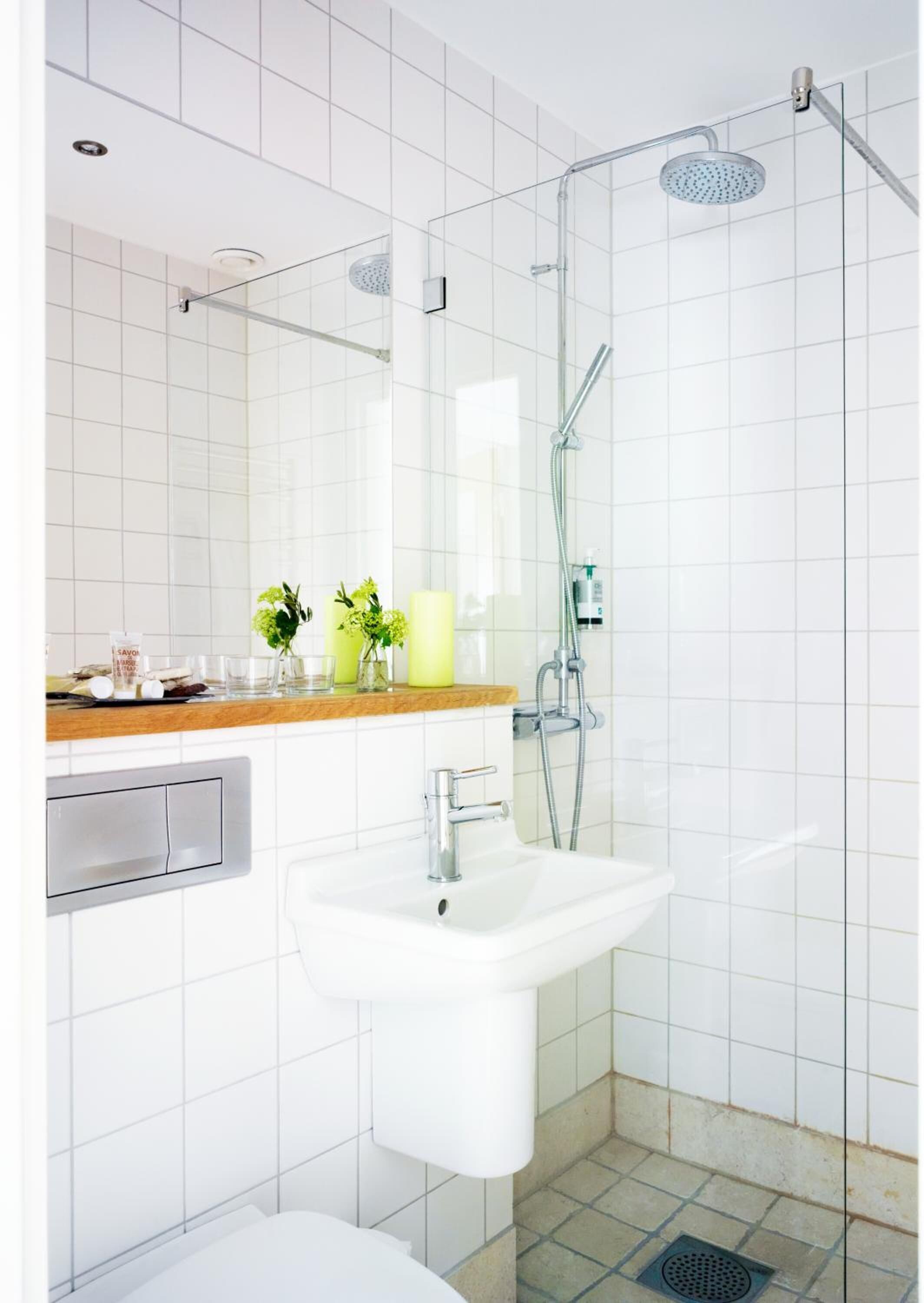 A modern bathroom with a glass shower enclosure, a white sink, and a wooden countertop with toiletries.