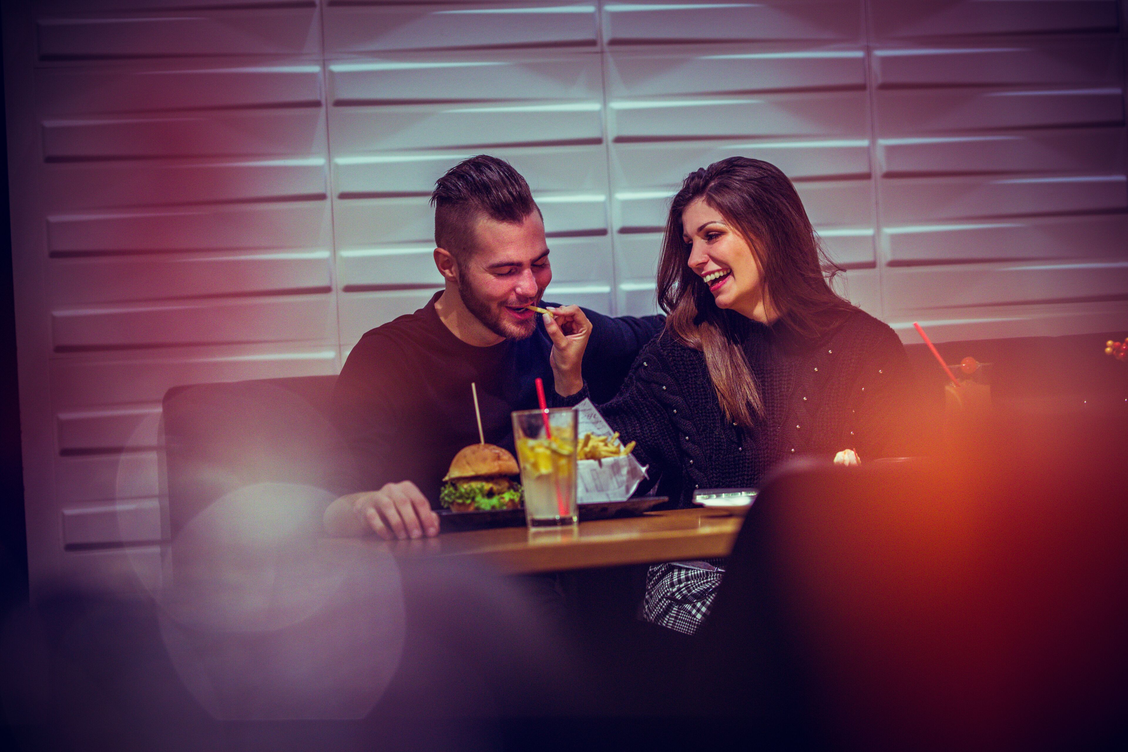 Een eettafel met een hamburger en een drankje.