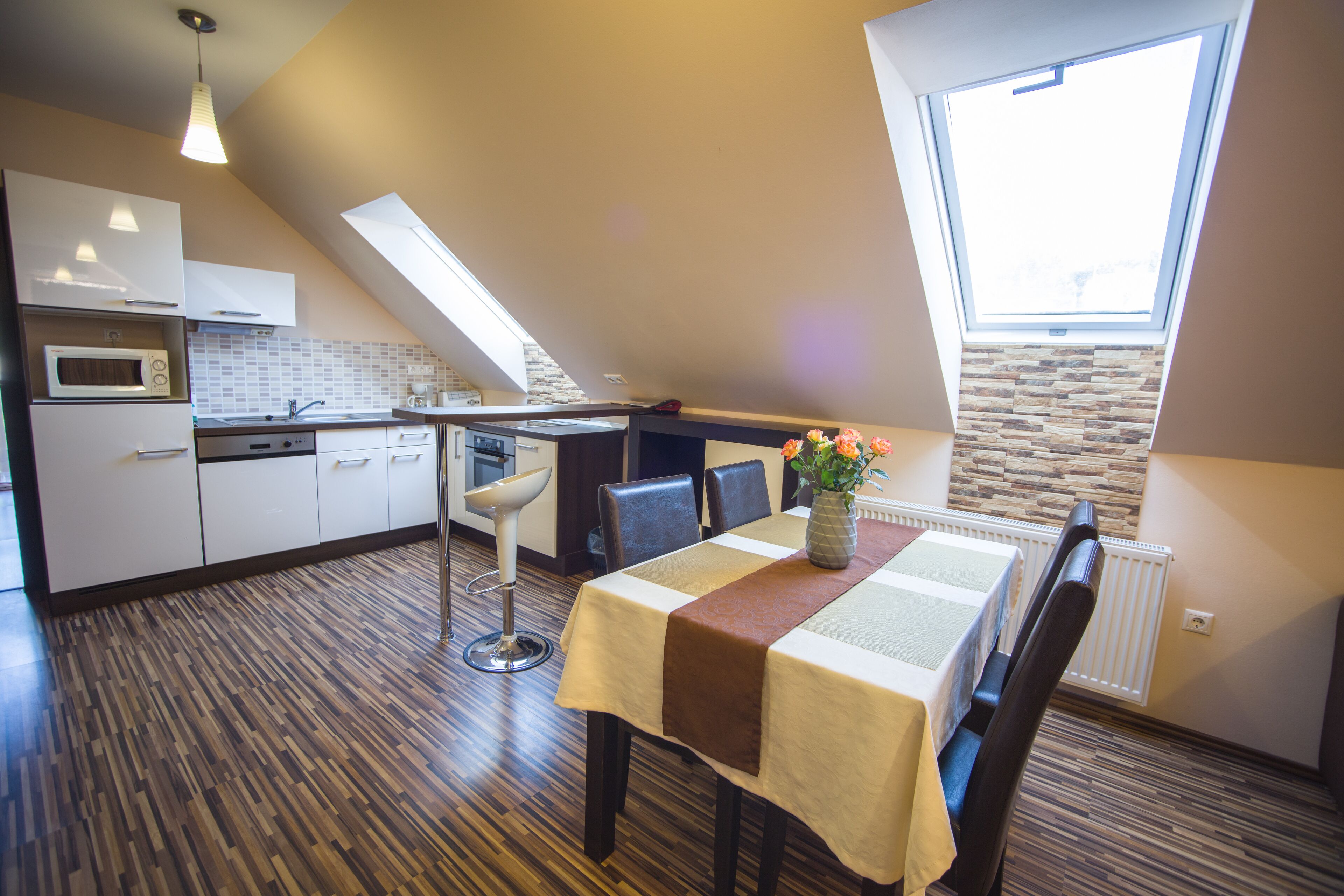 A modern kitchen with a skylight, a dining area with a table and chairs, and a view of the outdoors.