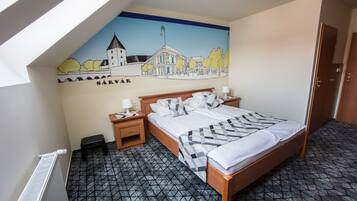 Un dormitorio con cama, mesitas de noche, un radiador, un mural en la pared y una puerta.