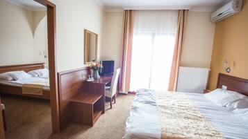 Une chambre d’hôtel avec deux lits, un bureau, une chaise, un miroir et un appareil de climatisation.