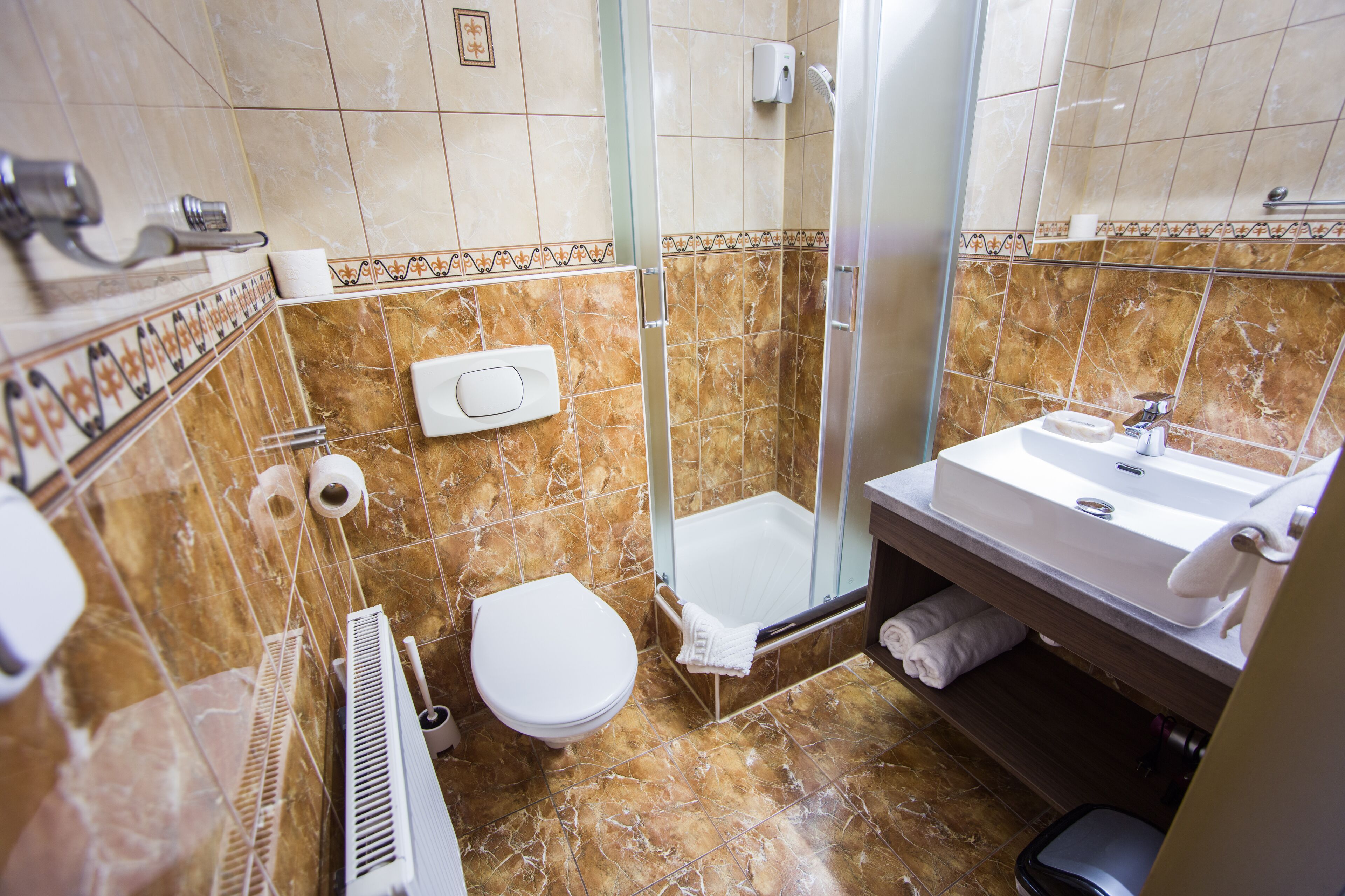 A bathroom with a toilet, shower, and sink.
