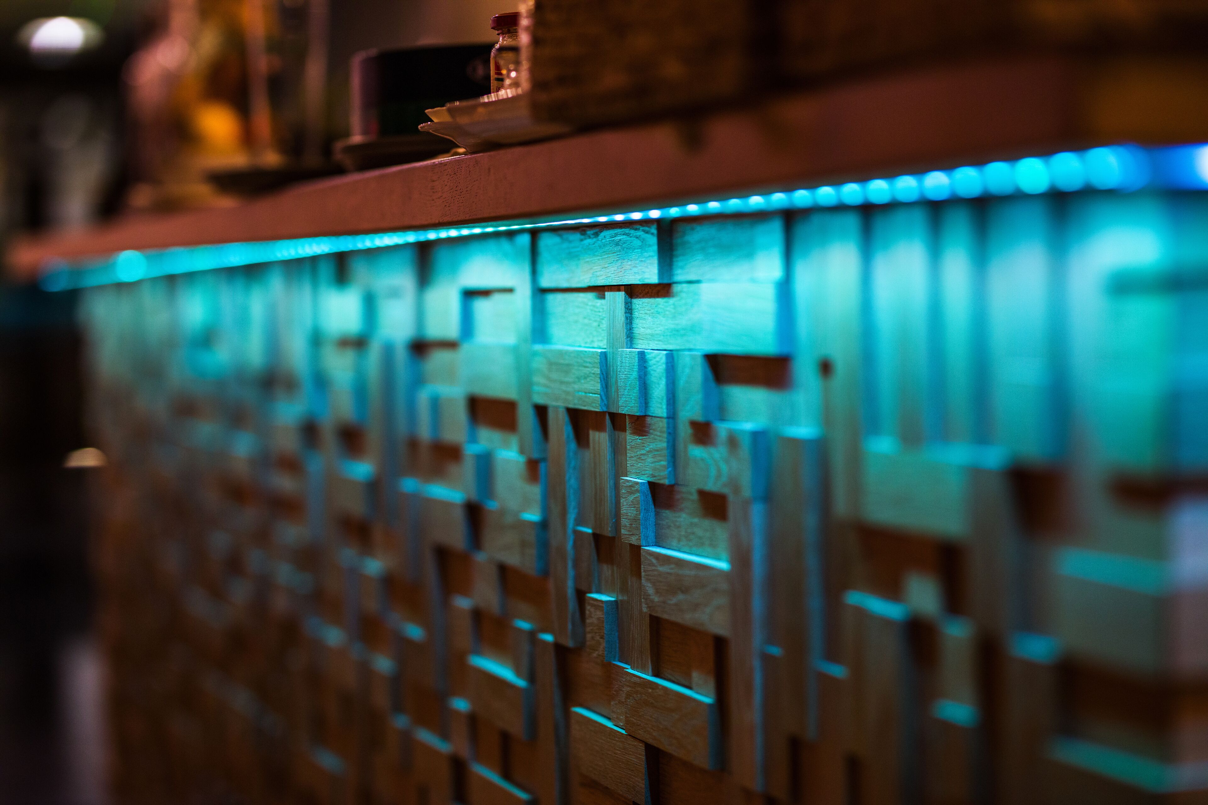 A close-up of a wooden wall with a geometric pattern and blue lighting.