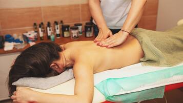 A massage therapy session in a room with a tiled wall and various bottles in the background.