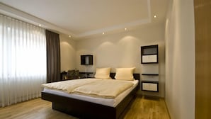 A modern bedroom with a large bed, wooden flooring, and built-in shelving. - Alte Post Hotel (Schoeppingen)