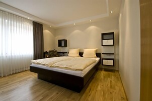 Un dormitorio moderno con una cama grande, suelo de madera y estanterías empotradas.