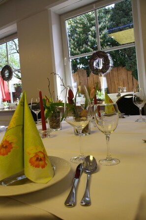 A table set with a plate, two wine glasses, a red candle, and a green napkin. - Alte Post Hotel (Schoeppingen)