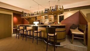 A bar area with a high counter, multiple stools, and a seating area with a bench and chairs. - Alte Post Hotel (Schoeppingen)