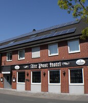 Un hotel con un letrero que dice 'Alte Post Hotel' y paneles solares en el tejado.