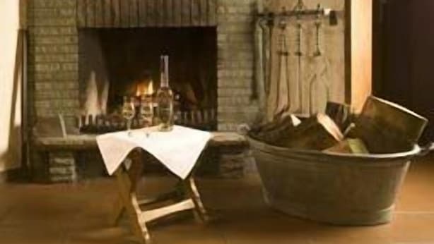 A rustic interior with a stone fireplace, a deer head mounted on the wall, and a rustic wooden table. - Alte Post Hotel (Schoeppingen)