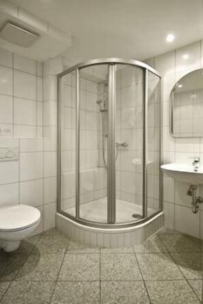 A bathroom with a glass-enclosed shower, a toilet, and a sink with a mirror. - Alte Post Hotel (Schoeppingen)