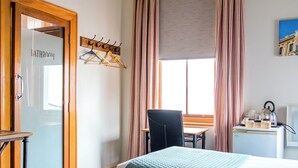A hotel room with two beds, a desk, a chair, and a bathroom door. - The Cambridge Hotel & Backpackers (Wellington)