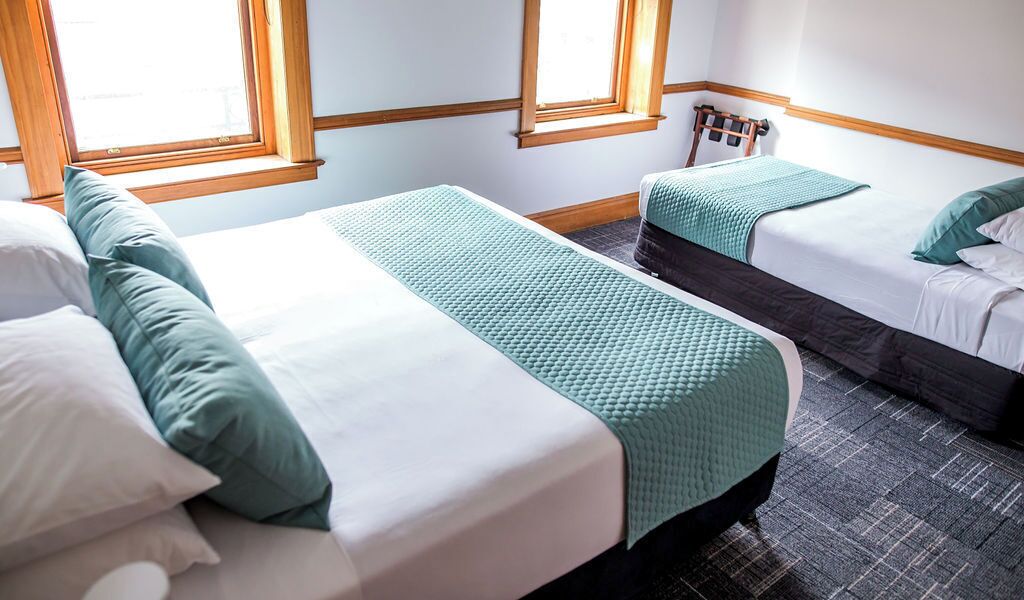 Habitación de hotel con dos camas, una ventana y un radiador.