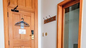 A wooden door with a "No Smoking" sign, a coat rack, and a "Bathroom" sign. - The Cambridge Hotel & Backpackers (Wellington)