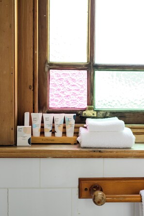 A bathroom with a wooden window sill holding toiletries and a towel. - The Cambridge Hotel & Backpackers (Wellington)