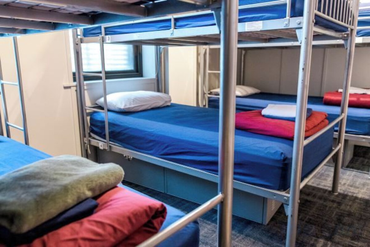 A bunk bed room with metal railings, a window, and a door.
