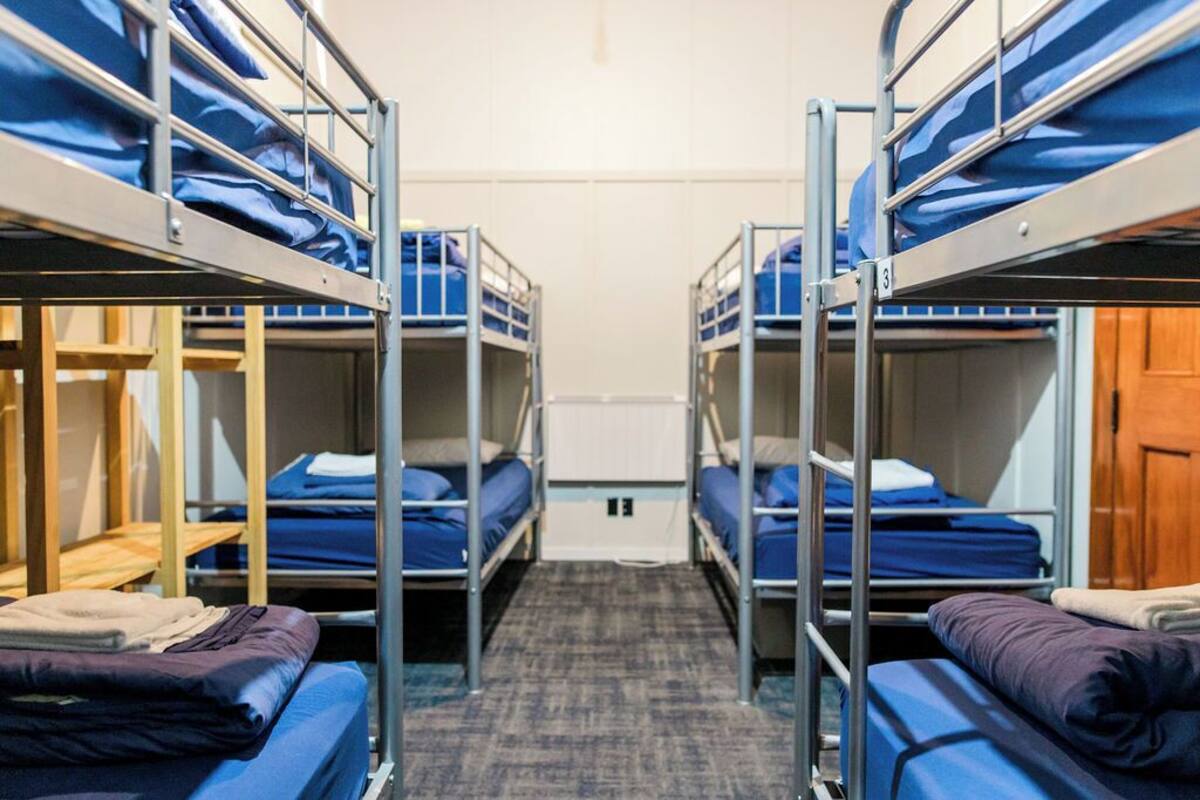 Un dormitorio con literas, un banco de madera y suelo cubierto de alfombra.