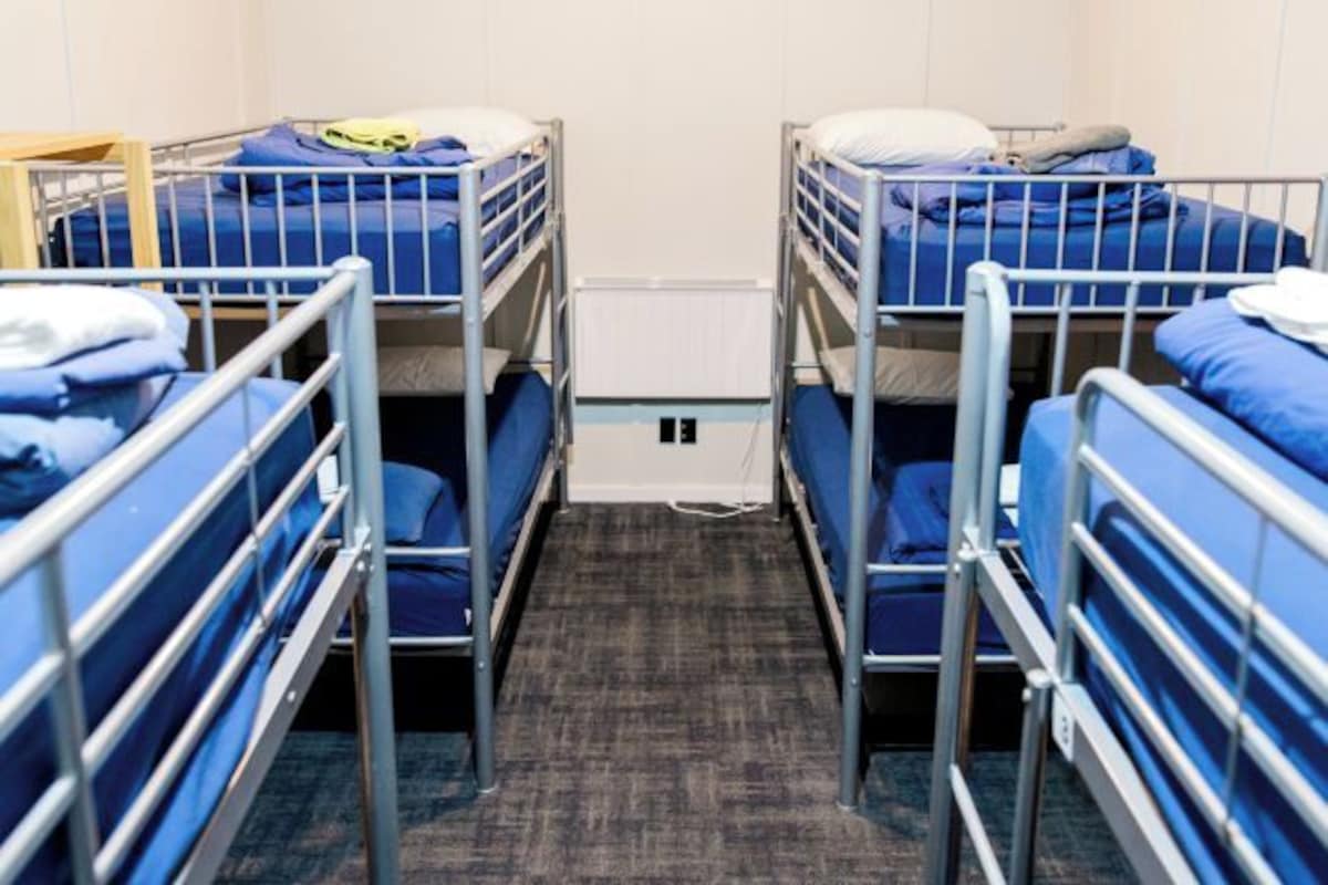A dormitory room with bunk beds, a carpeted floor, and a radiator.