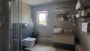 A modern bathroom with a glass shower enclosure, a toilet, a sink, and a mirror. - XO Residence (Arad)