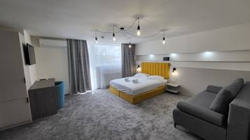 Una habitación de hotel moderna con cama, sofá, televisión y ventana con cortinas.