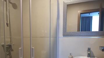 A modern bathroom with a glass-enclosed shower, a sink with a mirror, and a toilet.