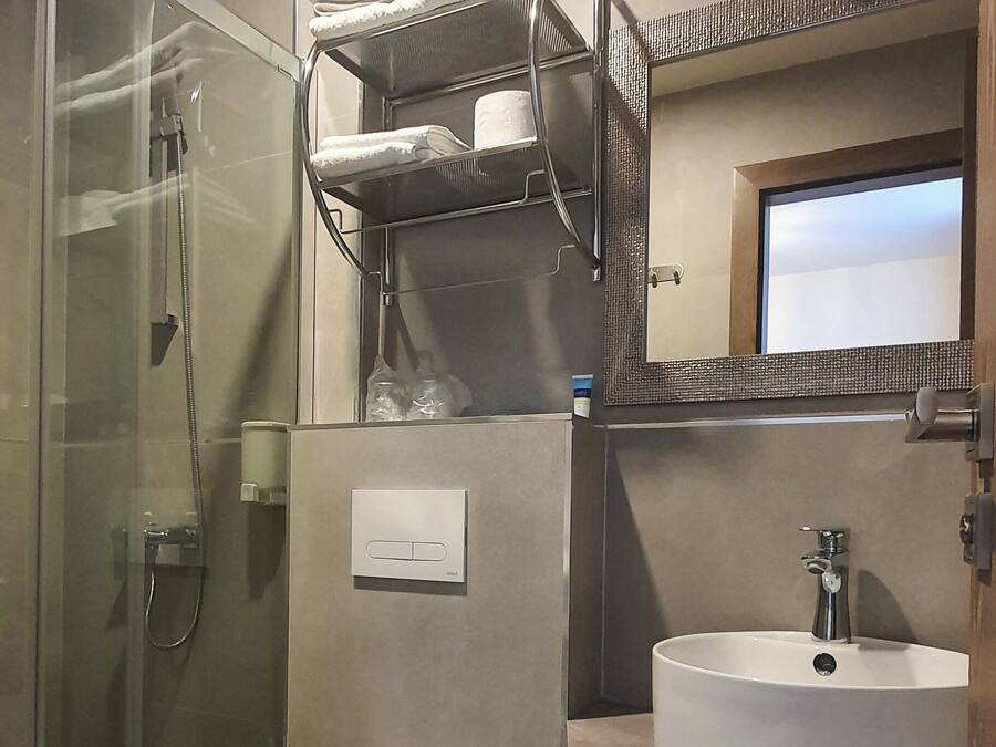 A modern bathroom with a glass-enclosed shower, a white toilet, a sink with a mirror, and a towel rack.