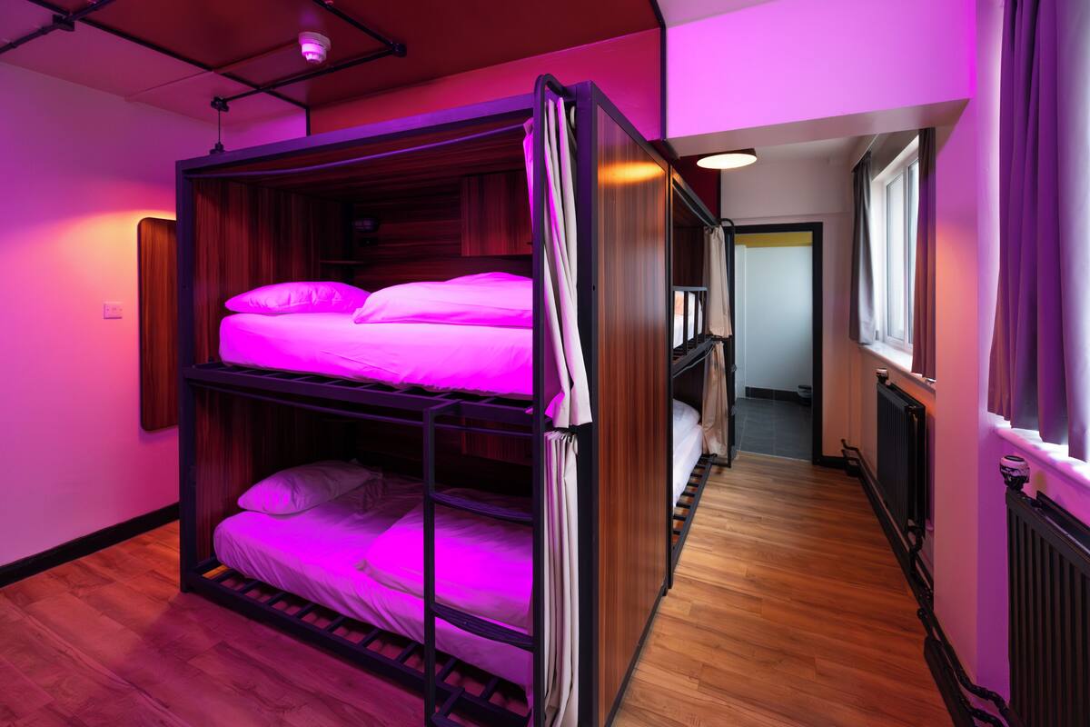 A bunk bed room with a wooden floor and a window on the right.