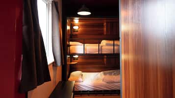 A bunk bed room with a wooden headboard, a bedside table, and a hanging light fixture.
