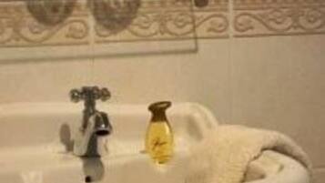 Un lavamanos de baño con un estante de vidrio encima, una toalla colgada en la pared y un borde decorativo de azulejos.