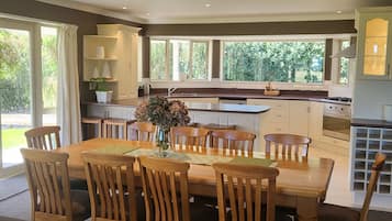 A modern kitchen with a dining area, large windows, and a cozy seating area.