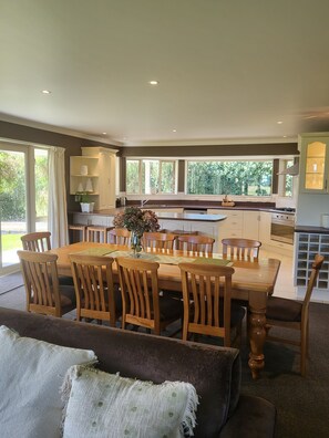 A modern kitchen with a dining area, large windows, and a cozy seating area. - Misty Peaks Guesthouse (Fox Glacier)